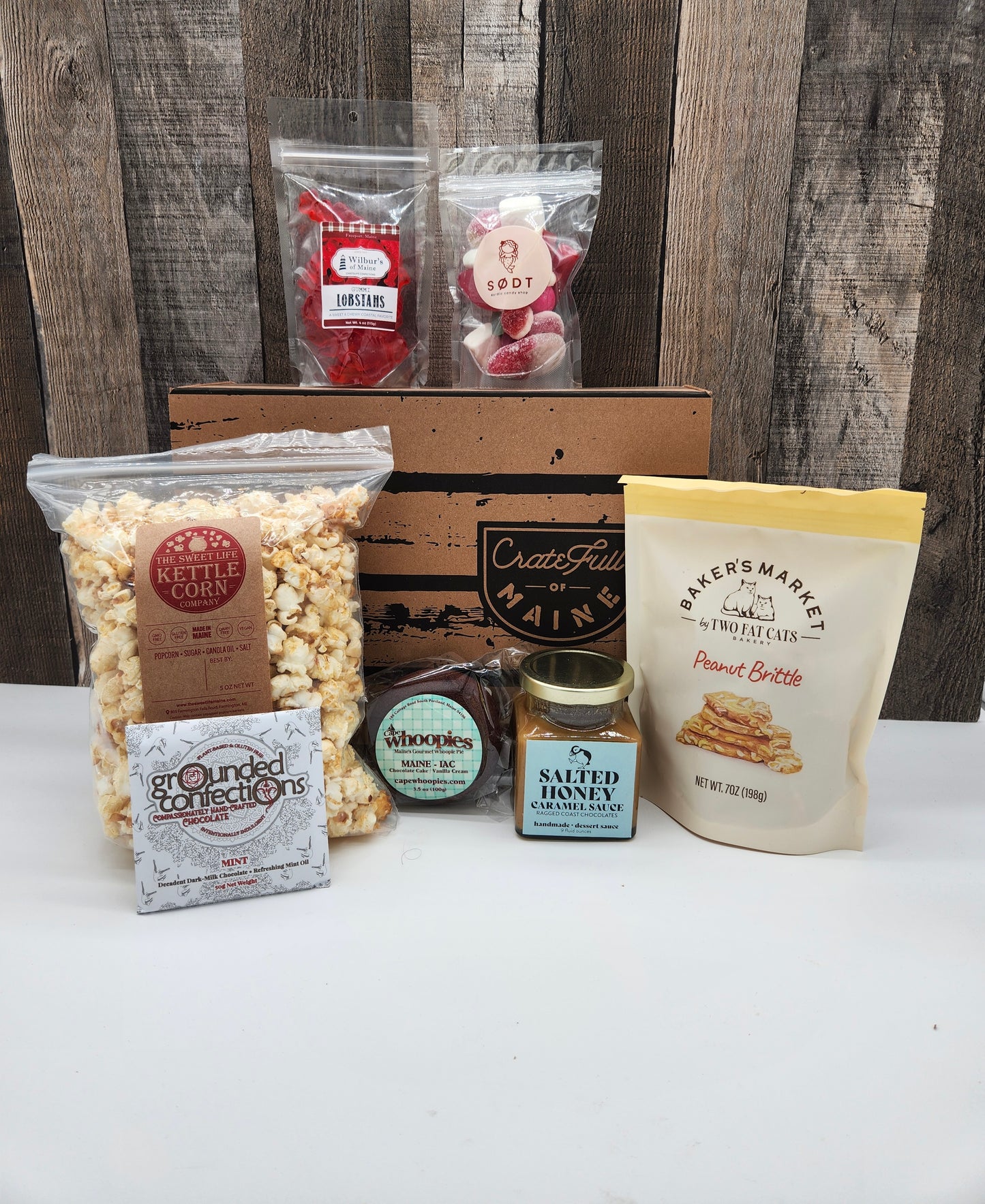 Assorted Maine snacks and treats on a white surface with a wooden background